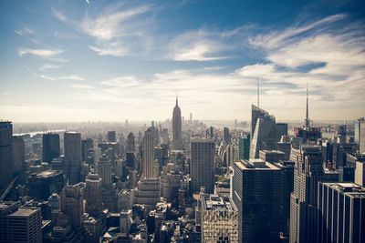 Aerial view of buildings in city against cloudy sky