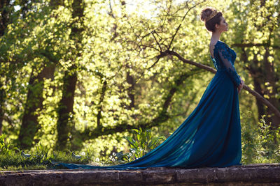 Woman standing by tree in forest