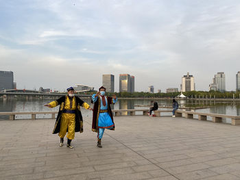 Rear view of people walking on cityscape against sky