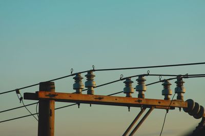 Low angle view of bird perching on cable against clear sky