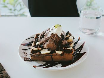 Close-up of waffle with chocolate ice cream in plate on table