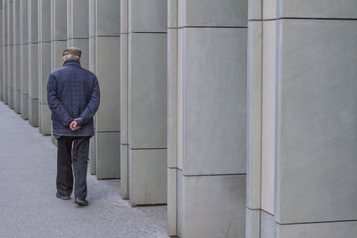 Man walking on sidewalk by colonnade