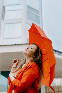 Beautiful woman standing with umbrella in rain