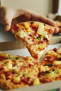 Close-up of hand holding pizza