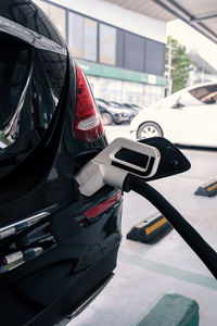 Power supply connects to plug-in electric vehicle or electric car at charging station in car park