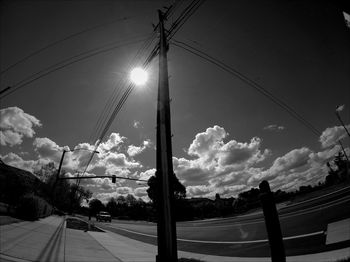 Low angle view of power lines against cloudy sky