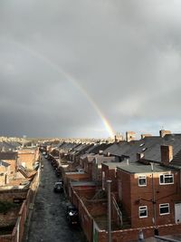 Rainbow over buildings in city against sky