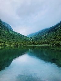 Scenic view of lake by mountains against sky