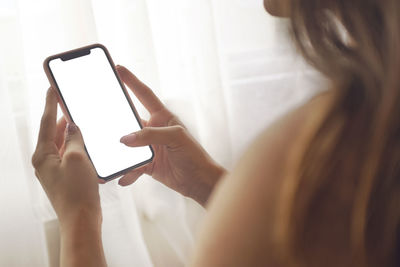 Cropped image of woman using mobile phone at home