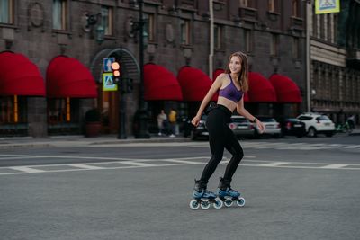 Full length of man skateboarding on road in city