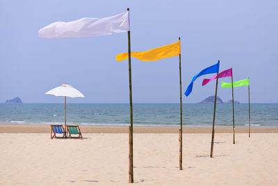 Deck chairs on beach against sky