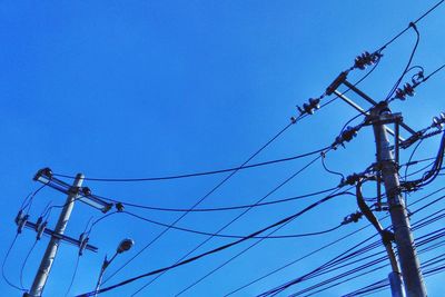 Low angle view of electricity pylon against blue sky