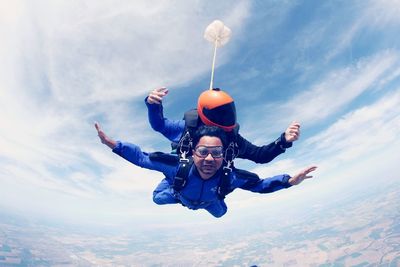 Low angle view of people paragliding against sky