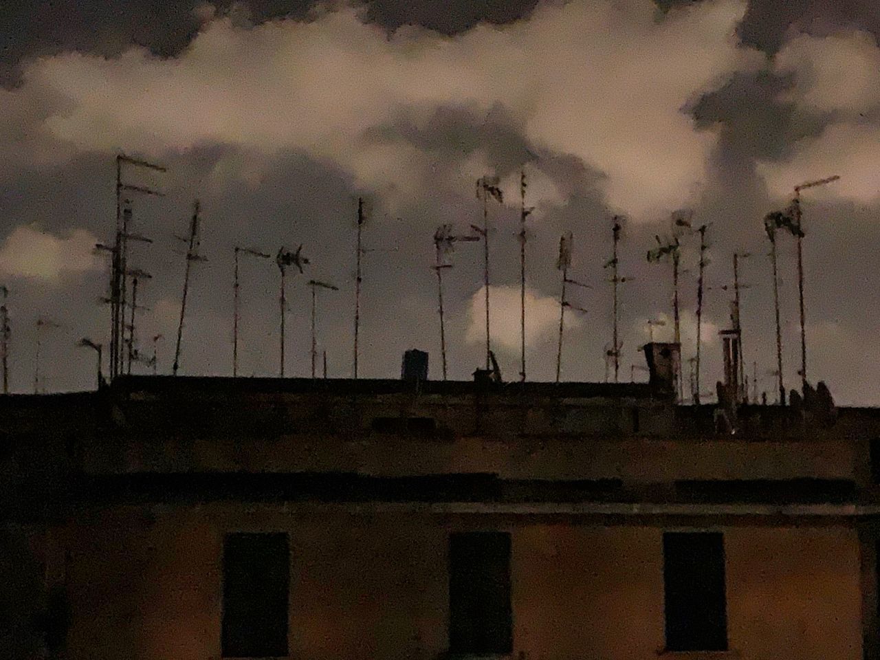 SILHOUETTE OF BUILDING AGAINST CLOUDY SKY AT DUSK