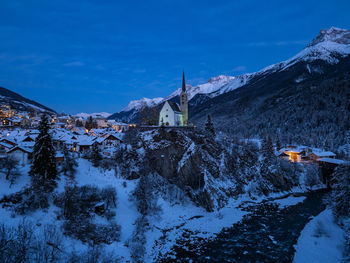 Snow covered buildings and mountains against blue sky