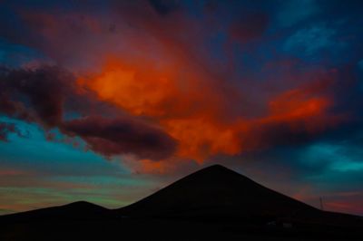 Scenic view of mountains against cloudy sky at sunset