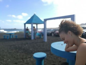 Happy woman by table looking down at sandy beach