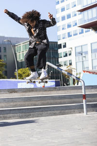 Sportsperson jumping while skateboarding at skateboard park