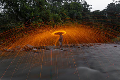Blurred motion of man standing by trees against sky