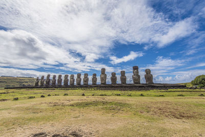 Statues on land against cloudy sky