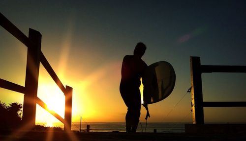 Silhouette of woman in sea at sunset