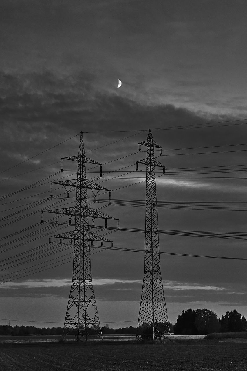 LOW ANGLE VIEW OF ELECTRICITY PYLONS ON FIELD AGAINST SKY