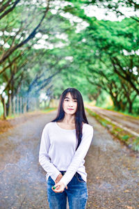 Portrait of young woman standing against tree