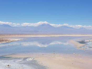 Scenic view of sea and mountains against blue sky