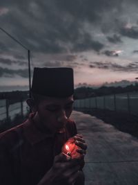 Man holding smart phone against sky during sunset