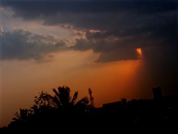 Silhouette of trees against cloudy sky