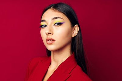 Portrait of young woman against red background