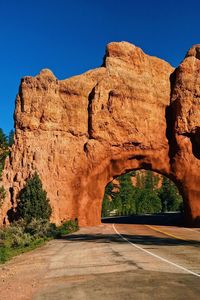 Road amidst rock formation against clear blue sky