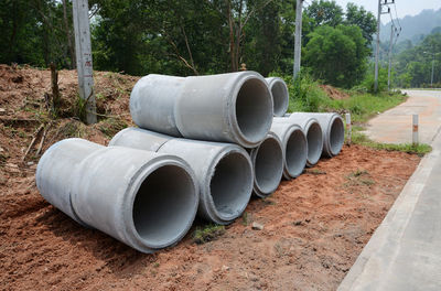 Stack of pipes on field by trees in forest