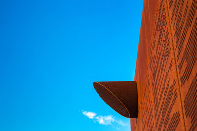 Low angle view of air duct on building against clear blue sky