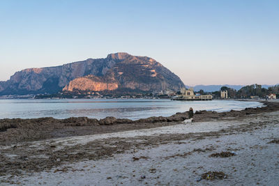 Scenic view of sea and mountains against clear sky