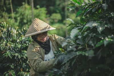 Woman wearing hat standing by plants