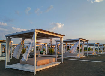 Lounge chairs by swimming pool at beach against sky