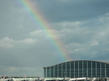 Low angle view of airport buildings against sky with rainbow