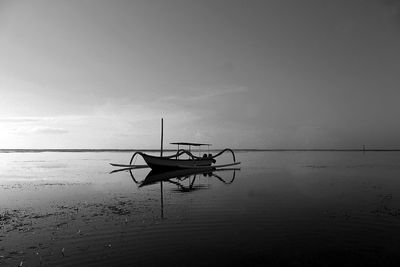 Silhouette ship on beach against sky