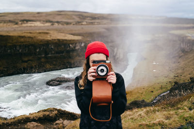 Woman photographing camera while standing on mountain