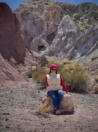 Front view of woman sitting on rock against  mountain