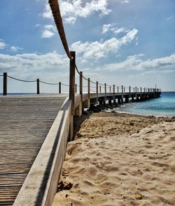 Pier on beach against sky