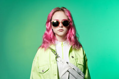 Young woman wearing sunglasses against blue background