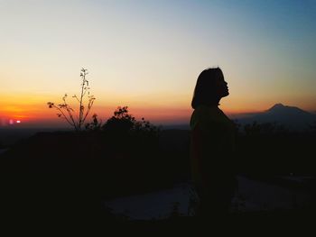 Silhouette man standing on field against sky during sunset