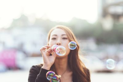 Close-up of young woman holding bubbles