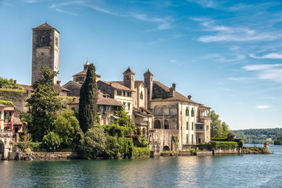 Buildings by river against sky in city