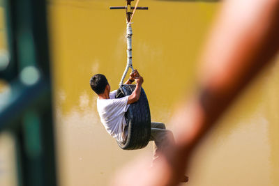 High angle view of man sitting on tire swing over lake