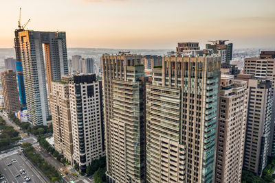 Modern buildings in city against sky during sunset