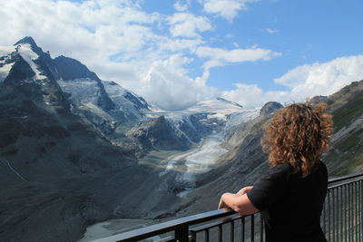 Women standing by railing looking at view of mountains against sky