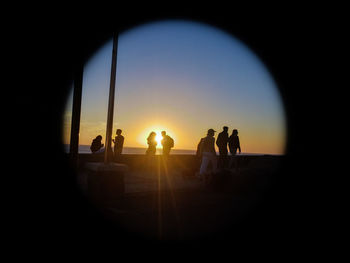 Silhouette people by sea against sky during sunset